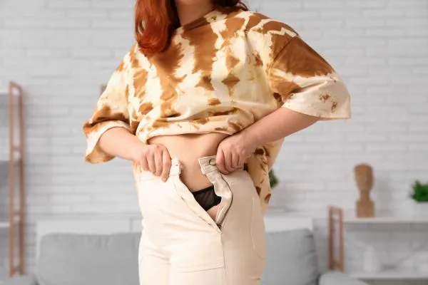 Image of woman trying to do her trousers up after pregnancy weight gain East Tilbury